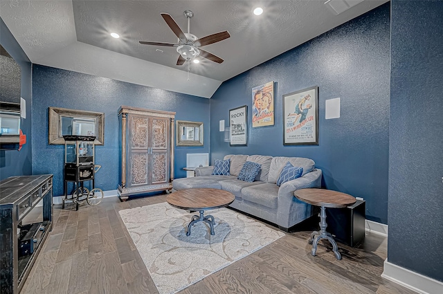 living room with ceiling fan, light hardwood / wood-style floors, and vaulted ceiling