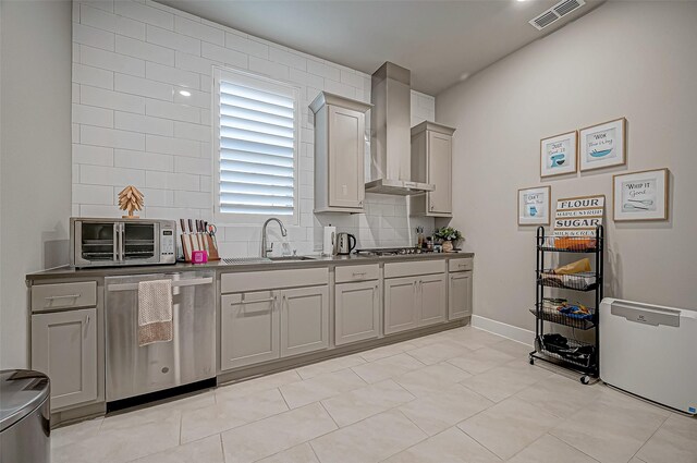 kitchen with sink, stainless steel appliances, gray cabinets, and wall chimney range hood