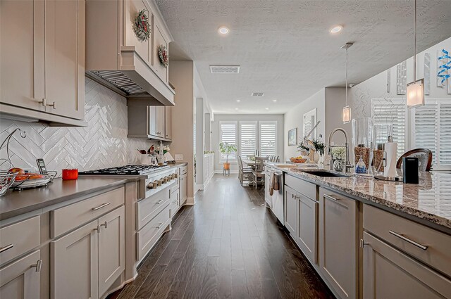 kitchen featuring light stone countertops, dark hardwood / wood-style flooring, a textured ceiling, sink, and hanging light fixtures