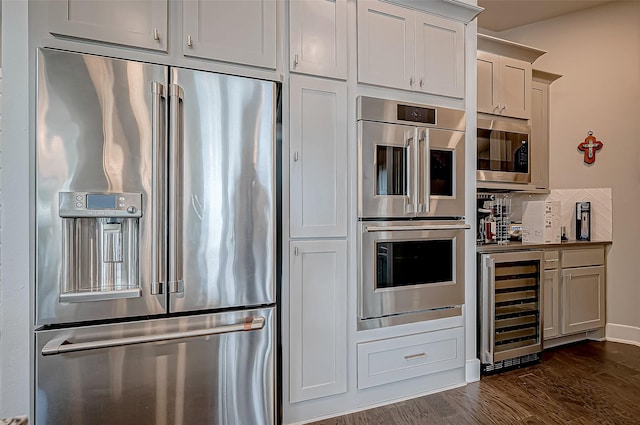 kitchen featuring decorative backsplash, dark wood-type flooring, beverage cooler, and appliances with stainless steel finishes