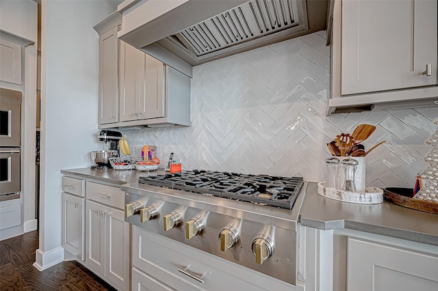 kitchen featuring decorative backsplash, dark wood-type flooring, stainless steel appliances, and custom range hood