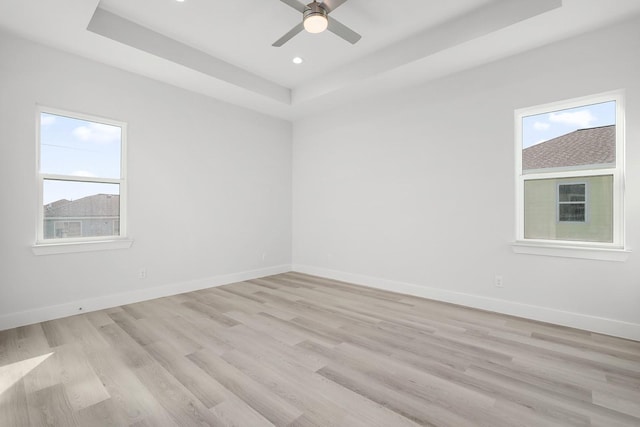 unfurnished room featuring ceiling fan, light hardwood / wood-style floors, and a raised ceiling