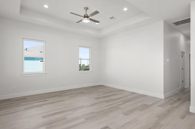 unfurnished room featuring ceiling fan, light hardwood / wood-style floors, and a raised ceiling