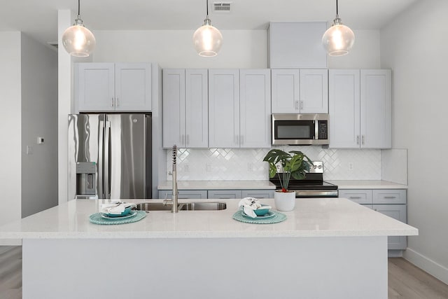 22803 Miramar Dr, Galveston, TX 77554 - kitchen featuring stainless steel appliances, a kitchen island with sink, decorative backsplash, and light wood-type flooring