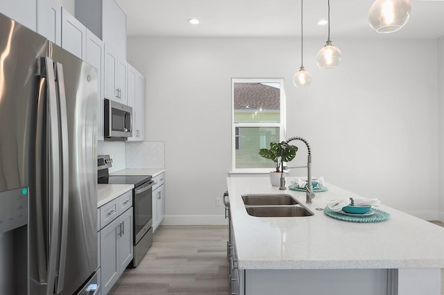 kitchen featuring appliances with stainless steel finishes, an island with sink, hanging light fixtures, and sink