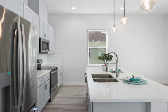 22803 Miramar Dr, Galveston, TX 77554 - kitchen with appliances with stainless steel finishes, light wood finished floors, a kitchen island with sink, recessed lighting, and tasteful backsplash