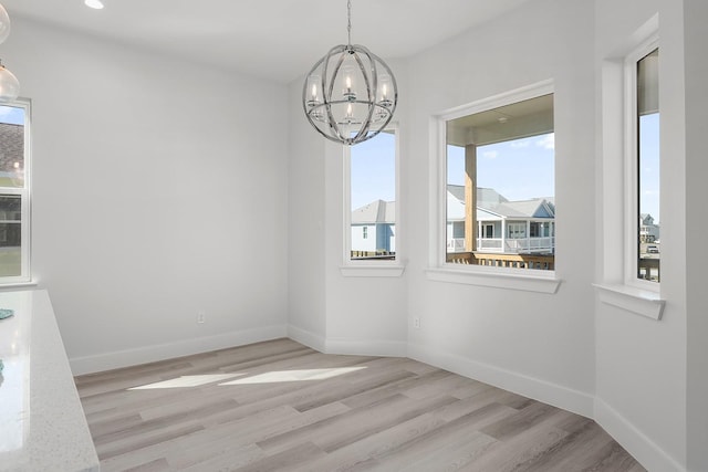 unfurnished dining area with light hardwood / wood-style floors and an inviting chandelier