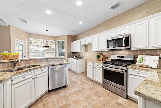 kitchen featuring appliances with stainless steel finishes, sink, white cabinets, a chandelier, and hanging light fixtures