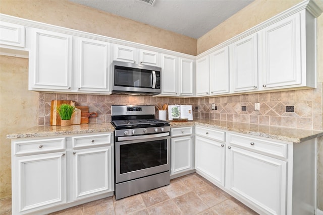 kitchen featuring white cabinets, decorative backsplash, light stone counters, and stainless steel appliances