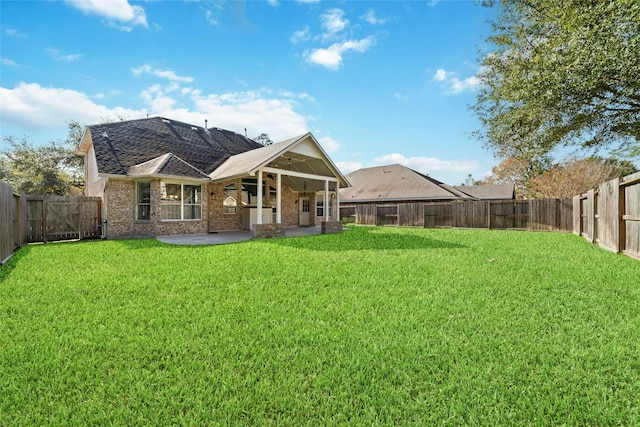 back of property with ceiling fan, a yard, and a patio