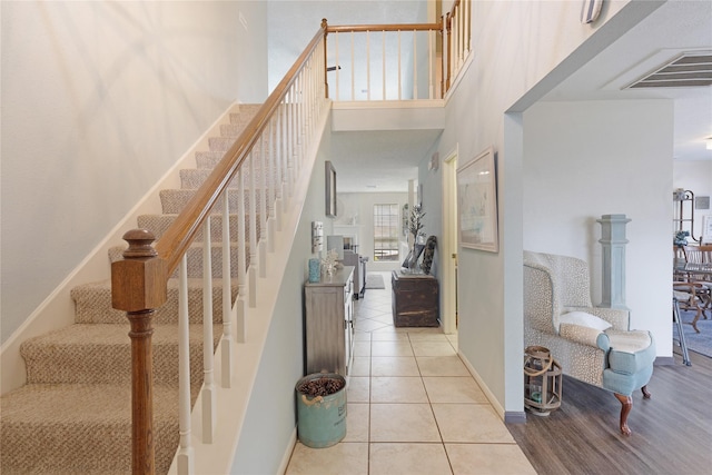 staircase with a towering ceiling and tile patterned flooring