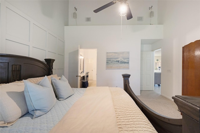 bedroom with a high ceiling, light carpet, ceiling fan, and a closet