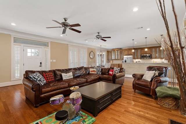 living room with crown molding, light hardwood / wood-style flooring, and ceiling fan with notable chandelier