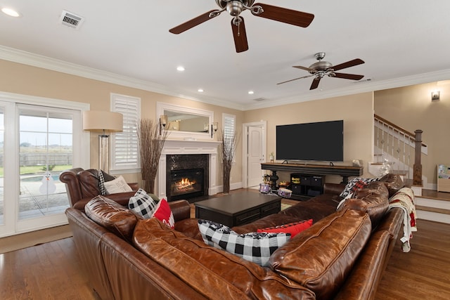 living room featuring dark hardwood / wood-style flooring, ceiling fan, ornamental molding, and a premium fireplace