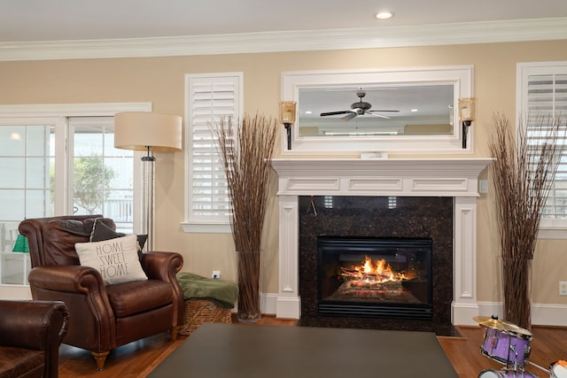 sitting room featuring ceiling fan, a high end fireplace, dark wood-type flooring, and ornamental molding