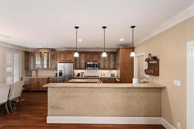 kitchen with light stone countertops, hanging light fixtures, dark hardwood / wood-style floors, kitchen peninsula, and appliances with stainless steel finishes