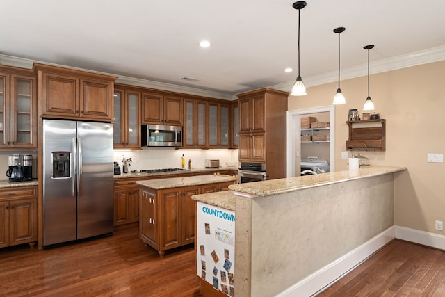 kitchen featuring hanging light fixtures, dark hardwood / wood-style flooring, washer / dryer, kitchen peninsula, and stainless steel appliances