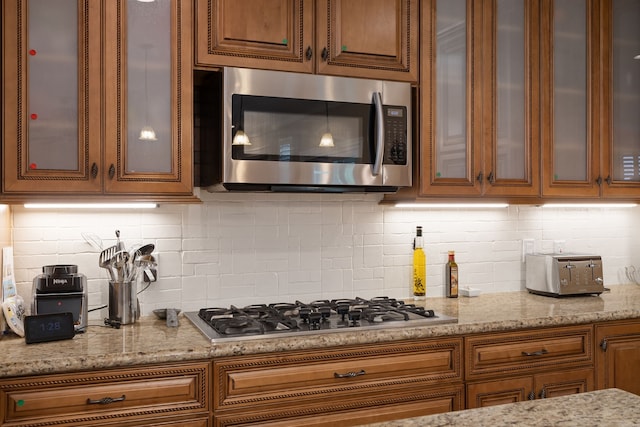 kitchen with light stone countertops, stainless steel appliances, and tasteful backsplash