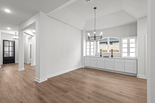 unfurnished dining area with light hardwood / wood-style floors and an inviting chandelier