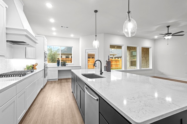 kitchen featuring premium range hood, a large island, stainless steel appliances, pendant lighting, and sink