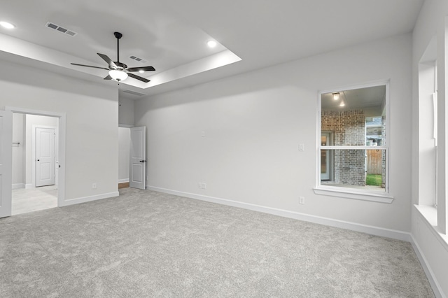 carpeted empty room with ceiling fan and a tray ceiling