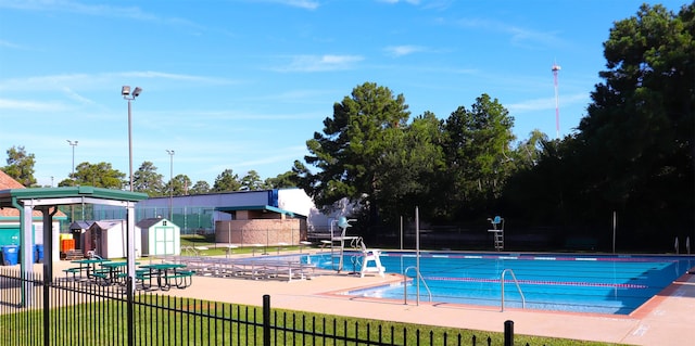 view of pool featuring a shed and a patio