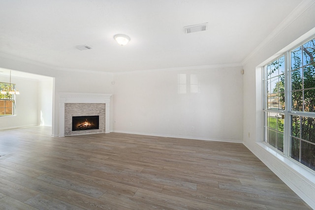 unfurnished living room with a chandelier, dark hardwood / wood-style flooring, plenty of natural light, and crown molding