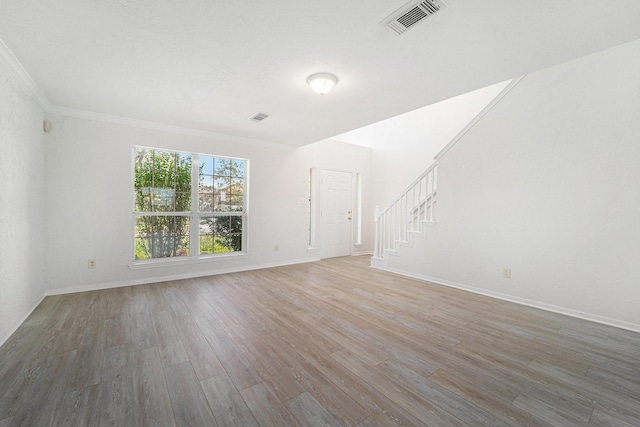 unfurnished living room featuring wood-type flooring and ornamental molding