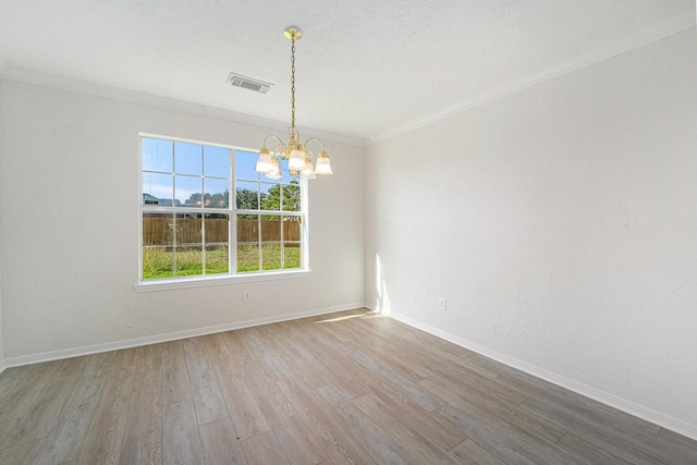 empty room with hardwood / wood-style flooring, a notable chandelier, and crown molding