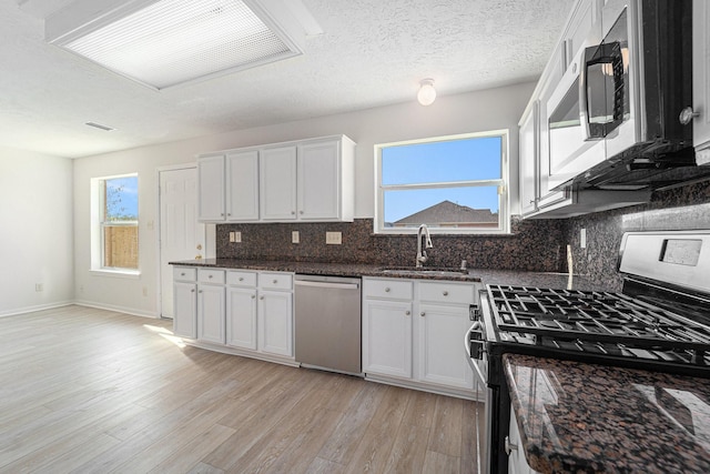 kitchen with white cabinets, stainless steel appliances, tasteful backsplash, and a wealth of natural light