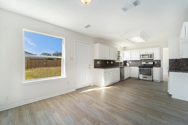 kitchen with decorative backsplash, white cabinetry, hardwood / wood-style floors, and stainless steel appliances