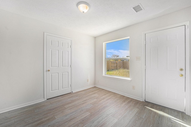 foyer entrance featuring a textured ceiling and light wood-type flooring