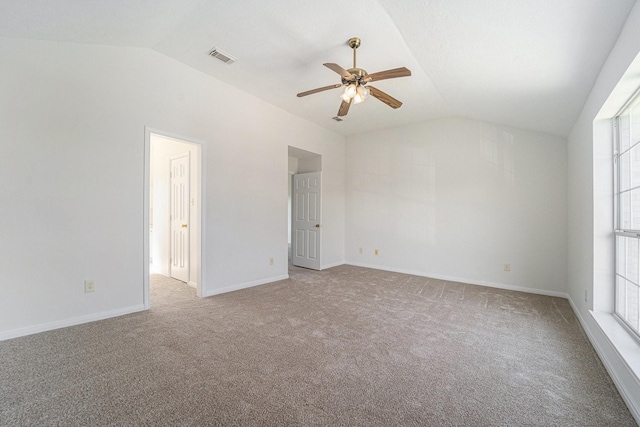 empty room with a wealth of natural light, ceiling fan, light colored carpet, and lofted ceiling