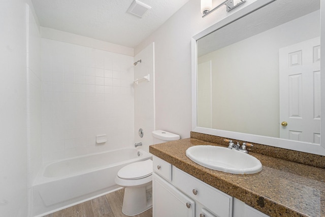 full bathroom with vanity, a textured ceiling, washtub / shower combination, hardwood / wood-style floors, and toilet