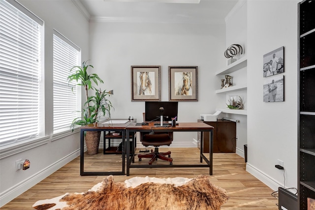 office space with built in shelves, light wood-type flooring, and ornamental molding