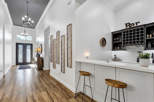 foyer entrance with hardwood / wood-style floors, crown molding, a high ceiling, and a chandelier