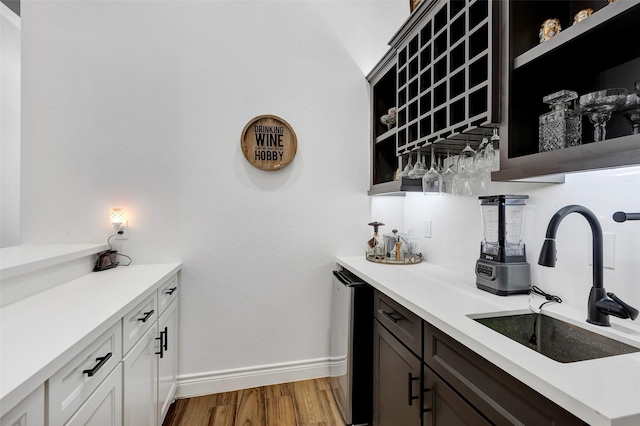 bar featuring sink, white cabinets, and hardwood / wood-style flooring