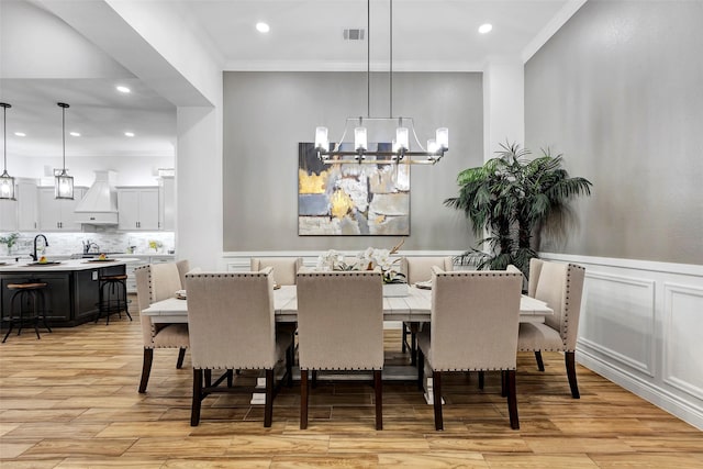 dining area with crown molding, light hardwood / wood-style flooring, and an inviting chandelier