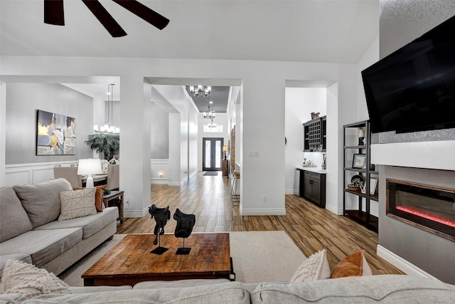 living room with light hardwood / wood-style floors and ceiling fan with notable chandelier