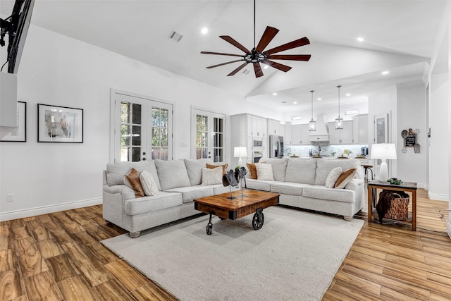 living room with ceiling fan, light hardwood / wood-style flooring, high vaulted ceiling, and french doors