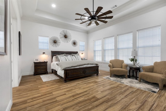 bedroom with a raised ceiling, ceiling fan, light hardwood / wood-style floors, and ornamental molding