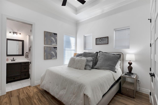 bedroom with light wood-type flooring, ornamental molding, ceiling fan, sink, and connected bathroom