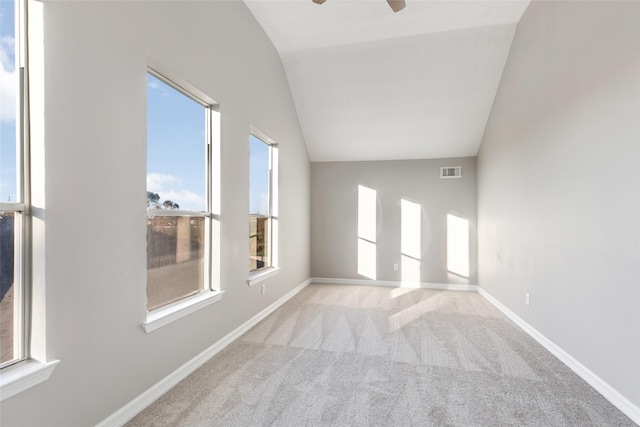 unfurnished room featuring light carpet, vaulted ceiling, plenty of natural light, and ceiling fan