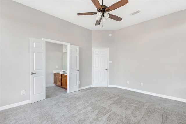 unfurnished bedroom with ceiling fan, light colored carpet, and ensuite bathroom