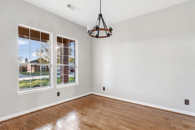 unfurnished room featuring hardwood / wood-style flooring and an inviting chandelier