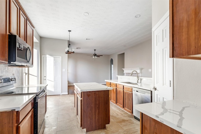 kitchen with ceiling fan, sink, a center island, pendant lighting, and appliances with stainless steel finishes