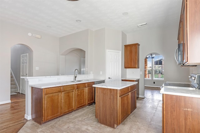 kitchen featuring kitchen peninsula, a textured ceiling, sink, range, and a center island