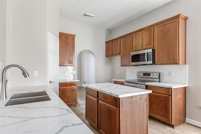 kitchen featuring light stone countertops, decorative backsplash, sink, and stainless steel appliances