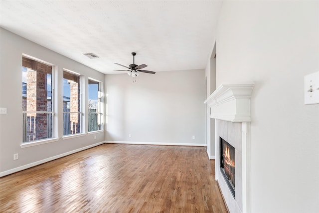 unfurnished living room featuring a high end fireplace, hardwood / wood-style flooring, and ceiling fan