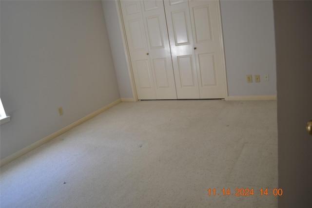 unfurnished bedroom featuring a closet and light colored carpet